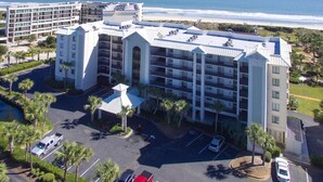 A multi-story hotel with a central courtyard, parking area, and a view of the beach. - Crescent C1D - Beach - Pool - Tennis - Very Nice! (Pawleys Island)