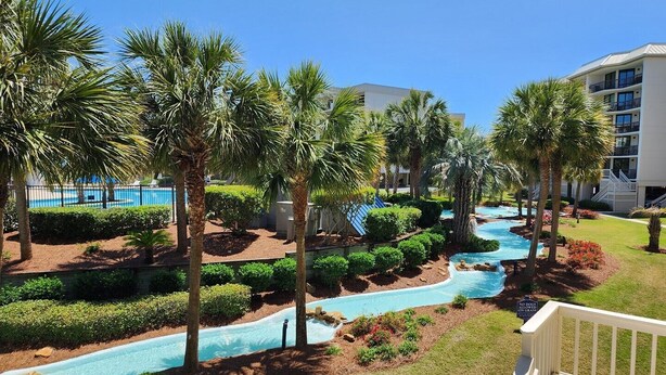A resort with a pool area, palm trees, and a building with balconies. - Crescent C1D - Beach - Pool - Tennis - Very Nice! (Pawleys Island)
