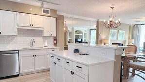 A modern kitchen with white cabinetry, a stainless steel dishwasher, and a marble countertop island. - Crescent C1D - Beach - Pool - Tennis - Very Nice! (Pawleys Island)