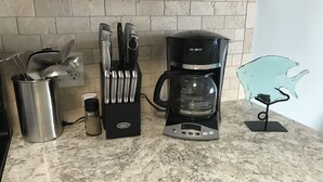 Una cocina con cafetera, bloque de cuchillos y salero sobre una encimera de mármol.