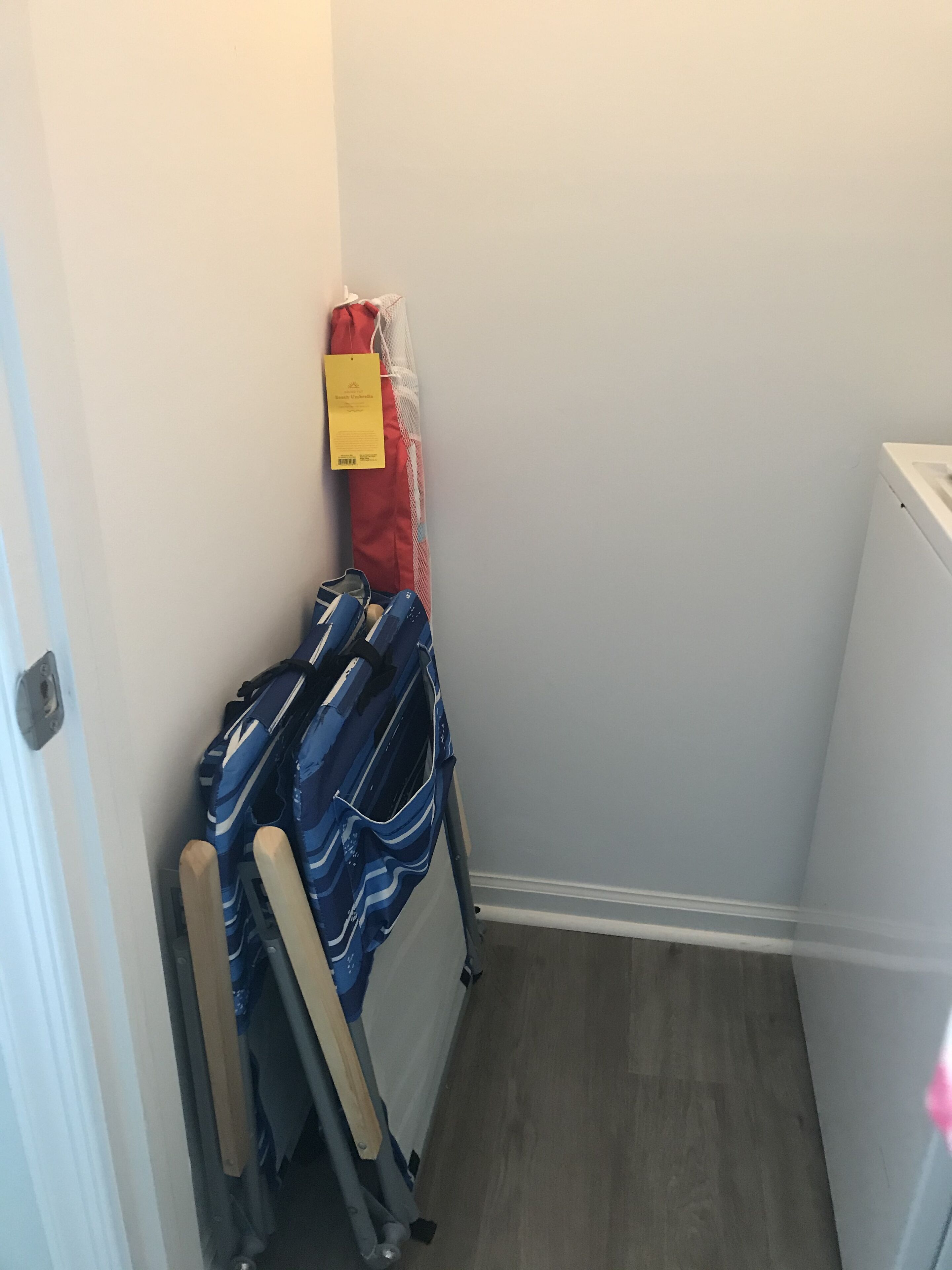 Een smalle gang met een houten vloer, een witte radiator en een blauwe koffer die tegen de muur staat.