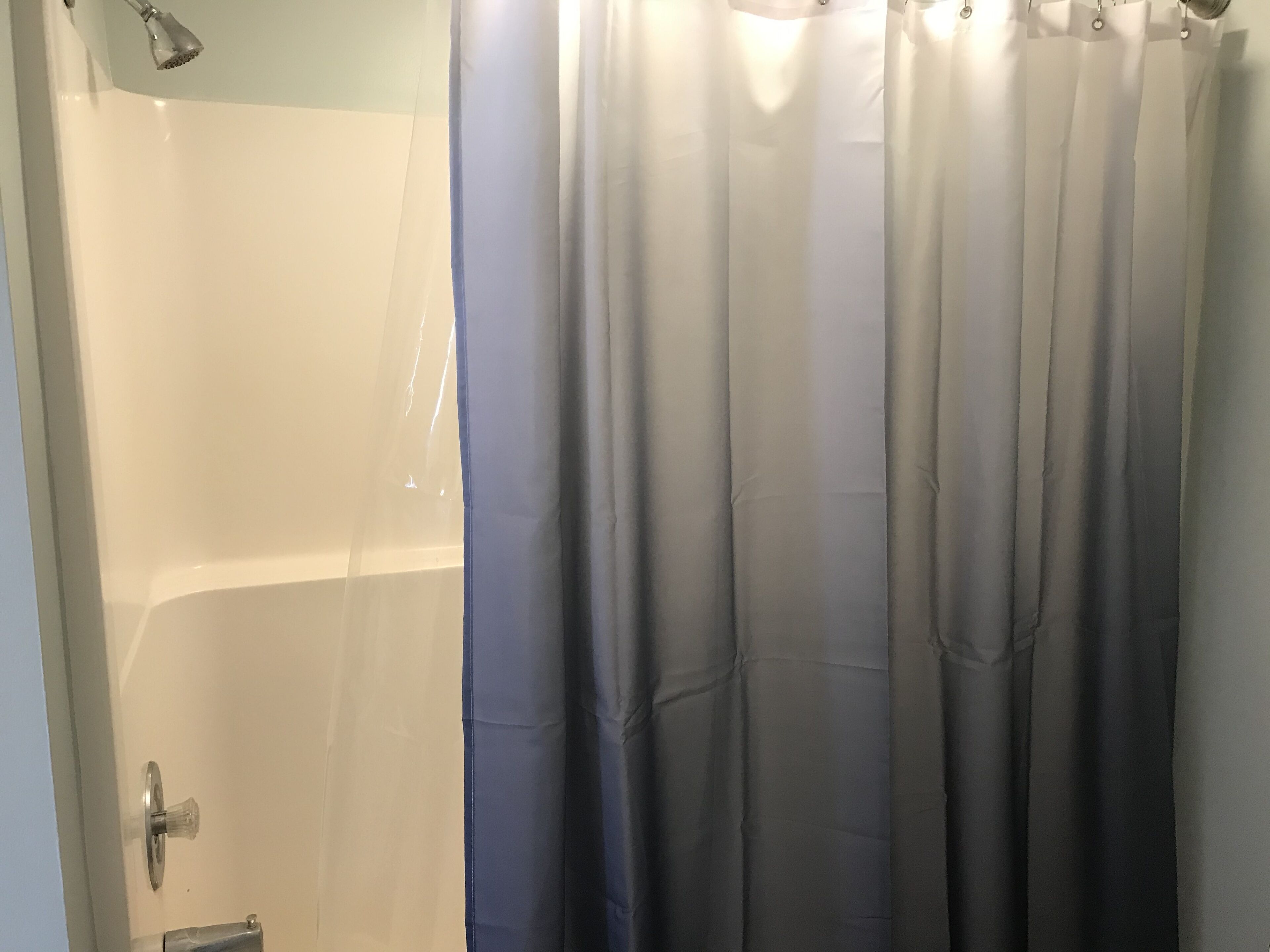 A bathroom with a shower, a glass door, and a curtain.
