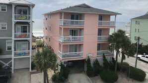 Un edificio rosa de varios pisos con balcones, un garaje y un letrero que dice 