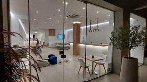 Un interior moderno con divisiones de vidrio, una recepción y zonas de estar.