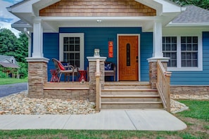 A house with a blue exterior, a wooden front door, and a stone pillar.