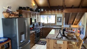 A modern kitchen with wooden cabinets, a stainless steel refrigerator, a built-in oven, and a large island with a bowl of fruit. - Northstar Mountain charm & luxury, near shuttle, 10 minutes to slopes, sleeps 6, (Truckee)
