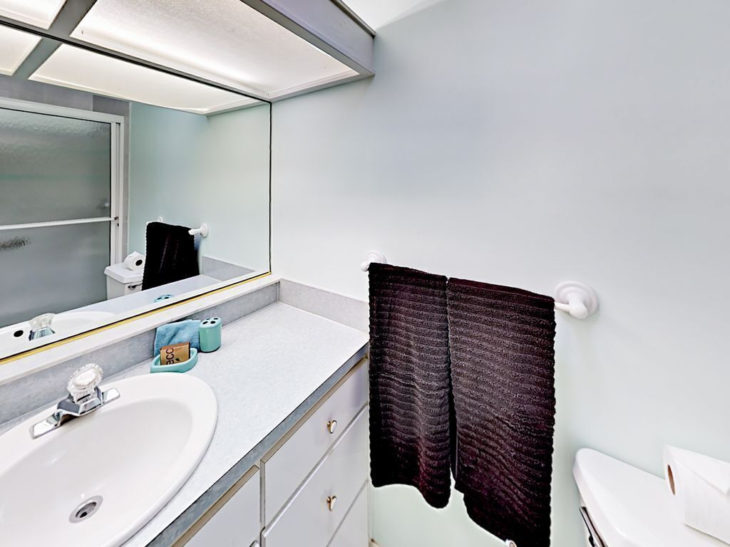 Une salle de bain avec un lavabo blanc, un miroir et une serviette accrochée au mur.