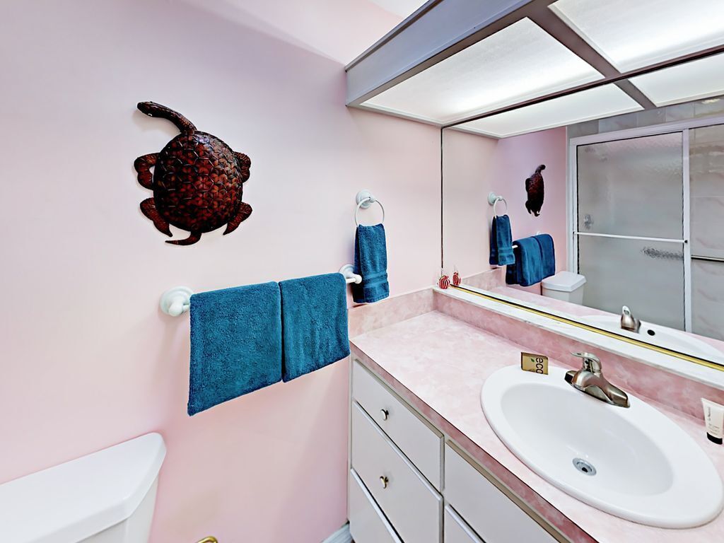 A bathroom with a pink wall, a white sink, and a mirror.