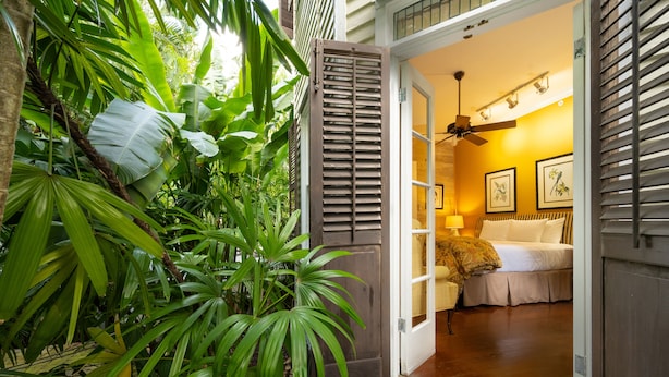 A room with a bed, a ceiling fan, and a window with blinds. - The Mermaid & Alligator (Key West)