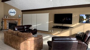 A living room with a fireplace, a large flat-screen TV, and a comfortable seating area.
