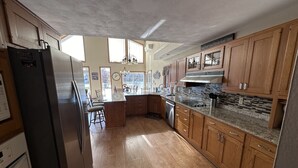 A spacious kitchen with wooden cabinets, a granite countertop, and a stainless steel refrigerator.