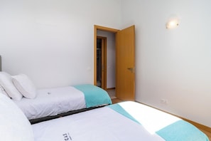 Un dormitorio con dos camas, una puerta de madera y una lámpara.