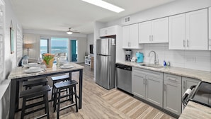 A modern kitchen with white cabinets, stainless steel appliances, and a marble countertop.