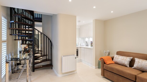 Een modern interieur met een trap, een keukenhoek en een woonkamer met een bank.