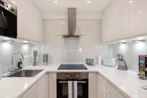A modern kitchen with stainless steel appliances, a double sink, and a toaster.