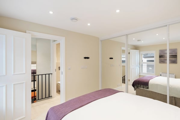 Un dormitorio con cama, espejo, puerta y un pequeño balcón.
