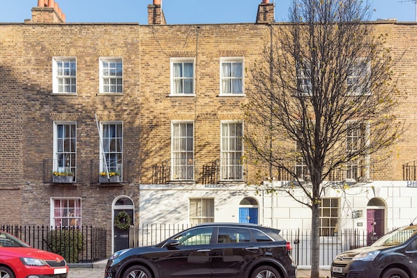 A row of terraced houses with a tree in front.