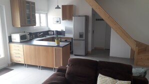 Eine moderne Küche mit Holzschränken, einer zentralen Kochinsel und einem integrierten Kühlschrank.