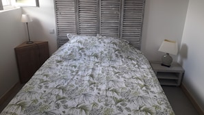Ein Schlafzimmer mit Bett, Nachttisch, Lampe und Fenster.
