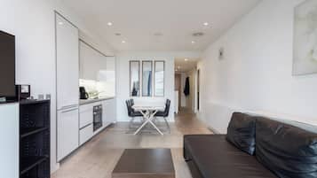A modern living space with a kitchen, dining area, and a leather couch.