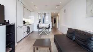 A modern living space with a kitchen, dining area, and a leather sofa. - 1BD Flat with City Views, Elephant & Castle (London)