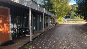 A motel with a covered outdoor seating area and a paved driveway.