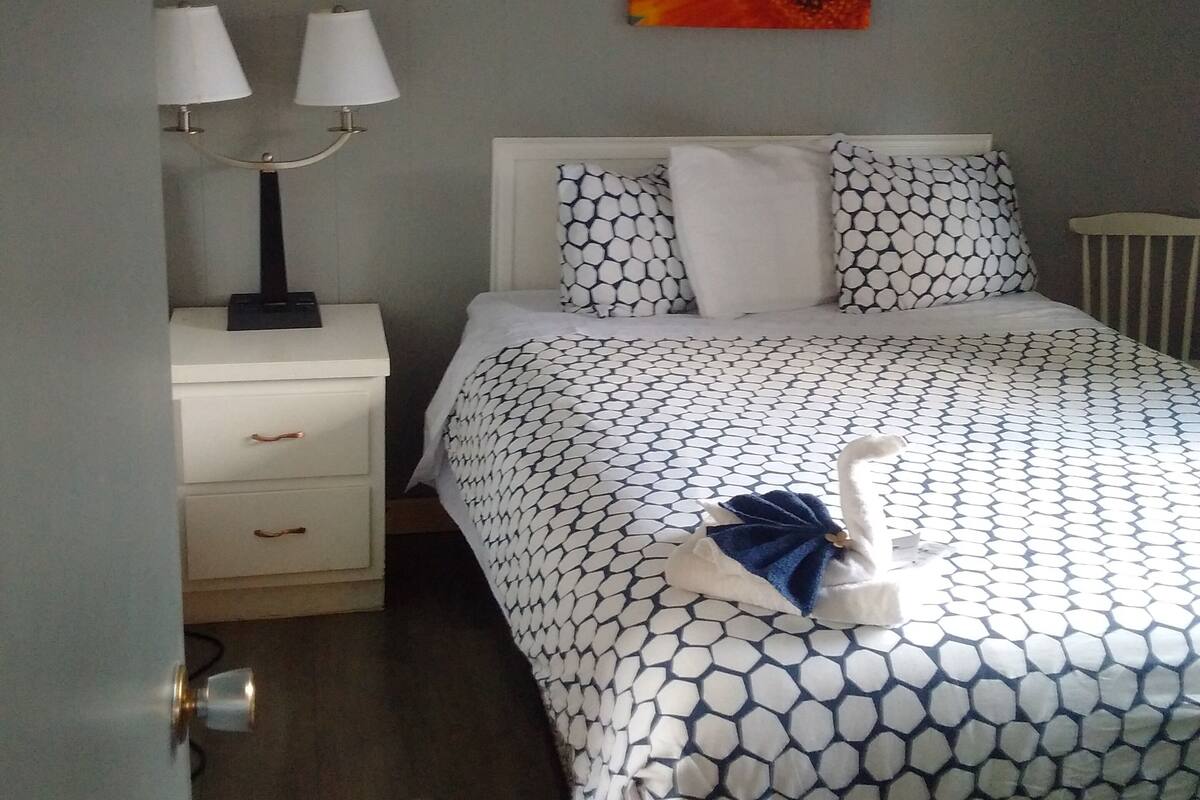 Un dormitorio con cama, dos lámparas de noche, un cuadro en la pared y un radiador.