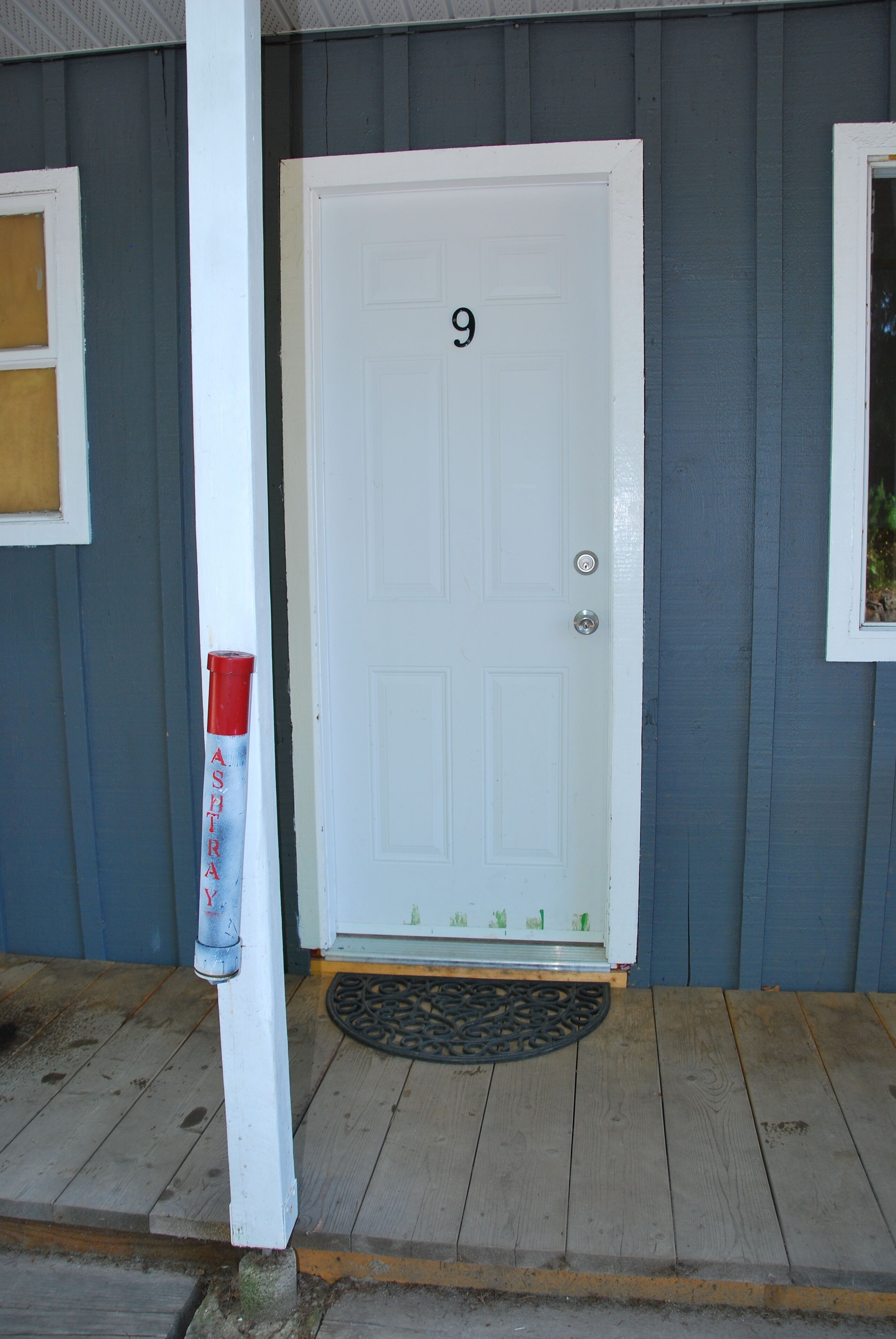 A white door with the number 9, a white doorbell, and a doormat.