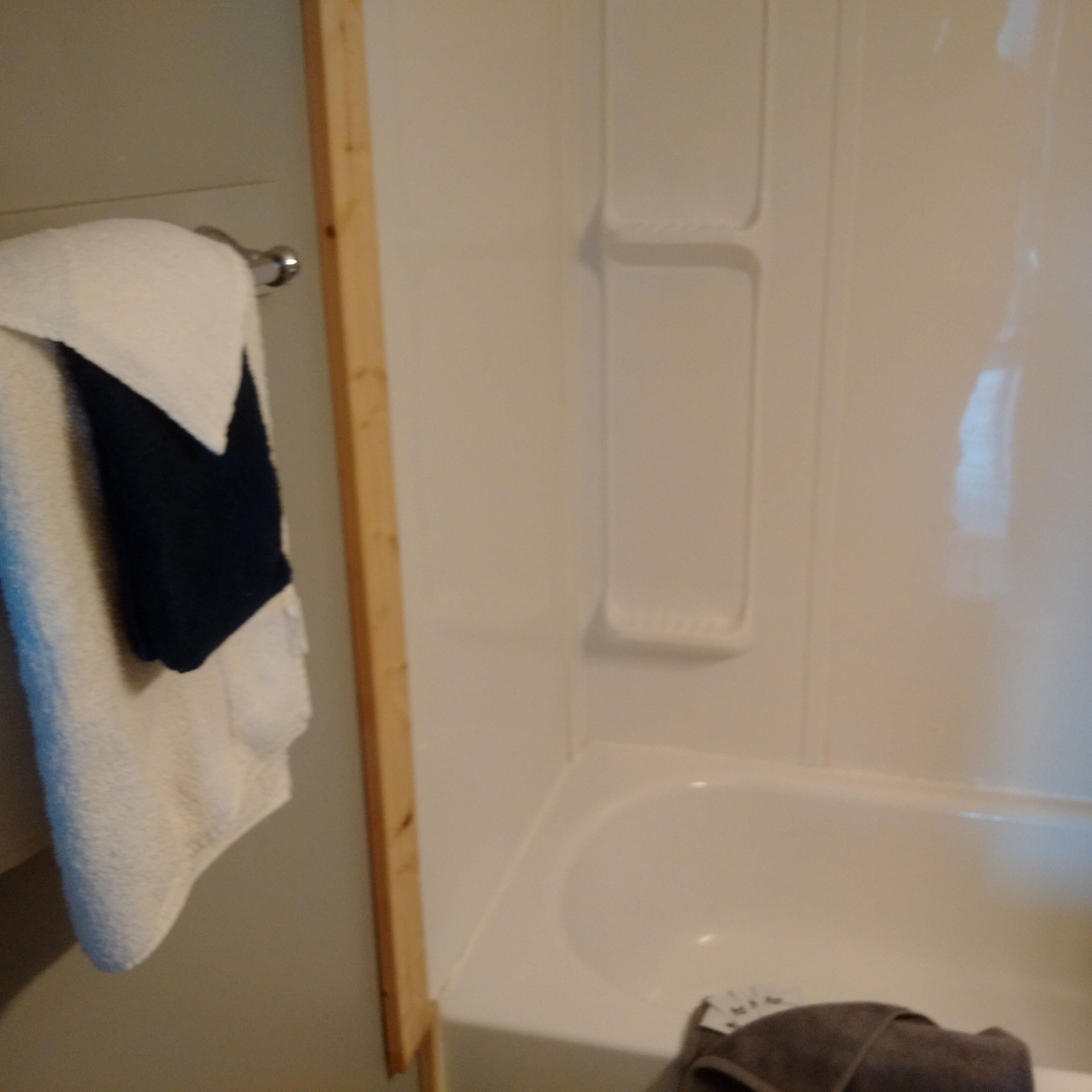 A bathroom with a bathtub, a towel rack, and a wooden door frame.