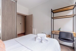Ein Hotelzimmer mit Bett, Schreibtisch, Stuhl und Kleiderschrank.