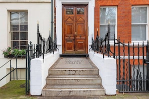 A front entrance with a wooden double door, a black wrought iron fence, and a set of concrete steps leading to the door. - Sublime 2BD Flat in the Heart of London, Zone 1 (London)