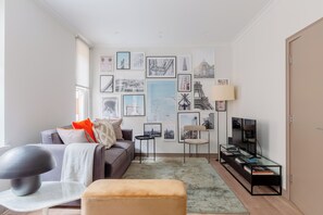 A modern living room with a sofa, ottoman, coffee table, and a flat-screen TV. - Sublime 2BD Flat in the Heart of London, Zone 1 (London)