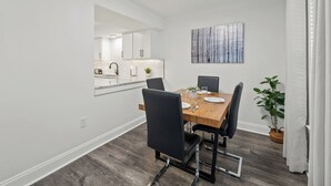 A dining area with a wooden table, black chairs, and a view into the kitchen. - Chefs Kitchen, King Beds, Smart TVs. Close to downtown! Dead End Street (Greenville)