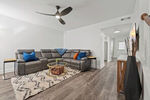 A modern living room with a sectional sofa, a round coffee table, and a ceiling fan.