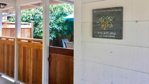 Eine hölzerne Veranda mit einem Schild, das Besucher im Orchard House willkommen heißt.