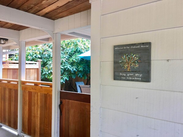 A wooden porch with a sign welcoming visitors to the Orchard House.