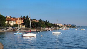 Une ville côtière où des bateaux sont amarrés le long de la rive, des bâtiments aux toits rouges et un ciel bleu dégagé.