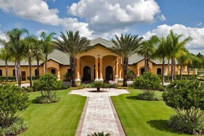 A large building with a central courtyard, surrounded by palm trees and well-maintained lawns.