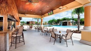 Un área de descanso al aire libre con piscina, sillas y bar.