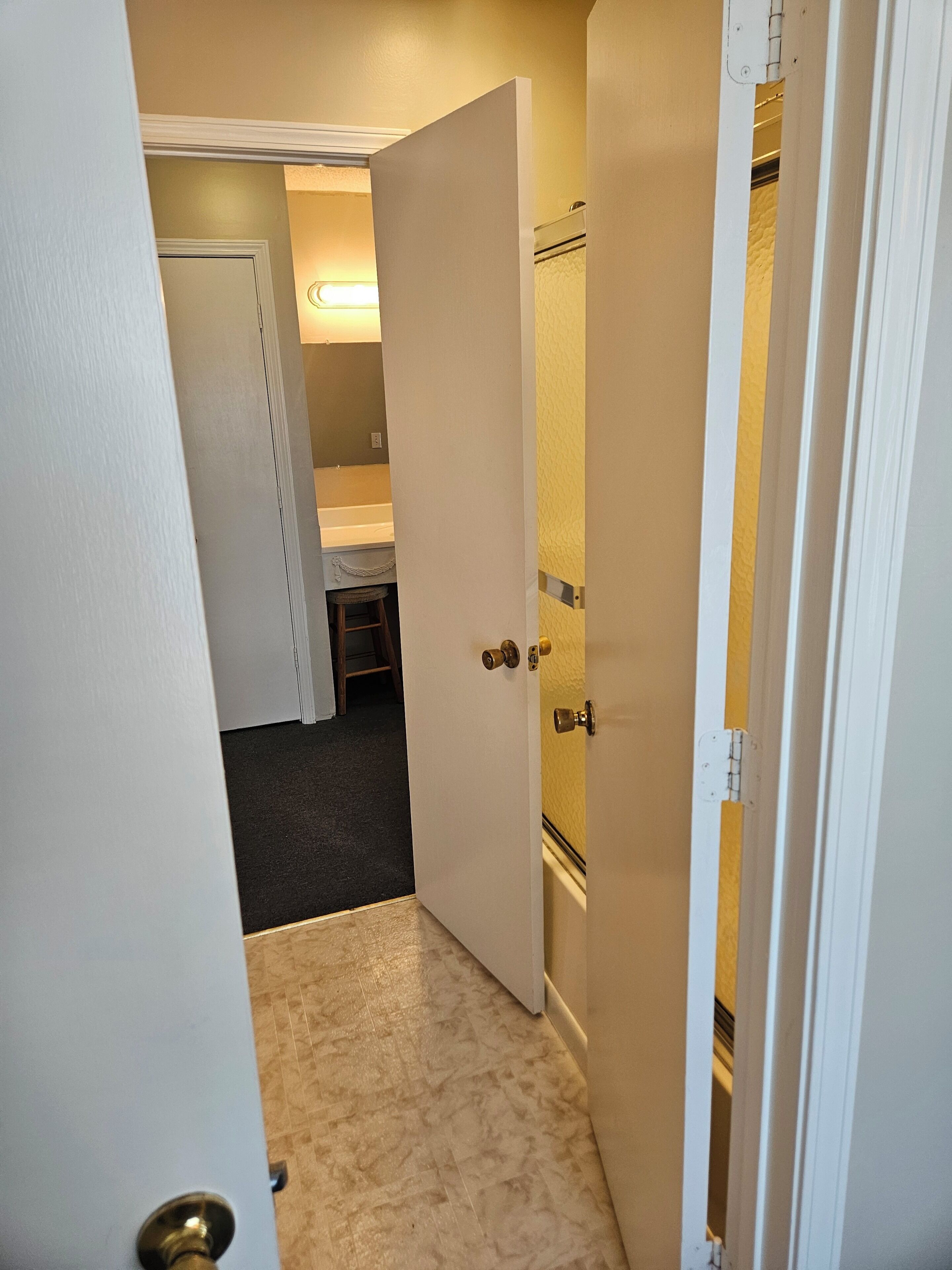 A narrow hallway with a door leading to a bathroom.