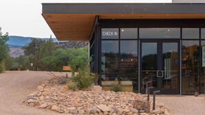 A modern building with a "CHECK IN" sign, a gravel driveway, and a wooden overhang.
