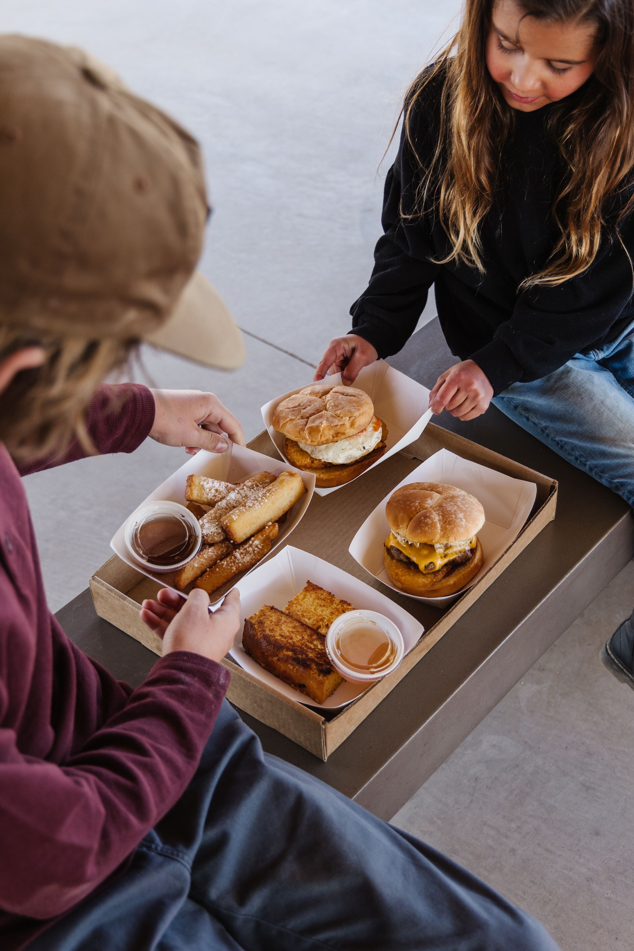 A table with food items including sandwiches, fries, and a drink.
