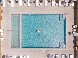 Una piscina al aire libre, sombrillas, sillones reclinables de piscina