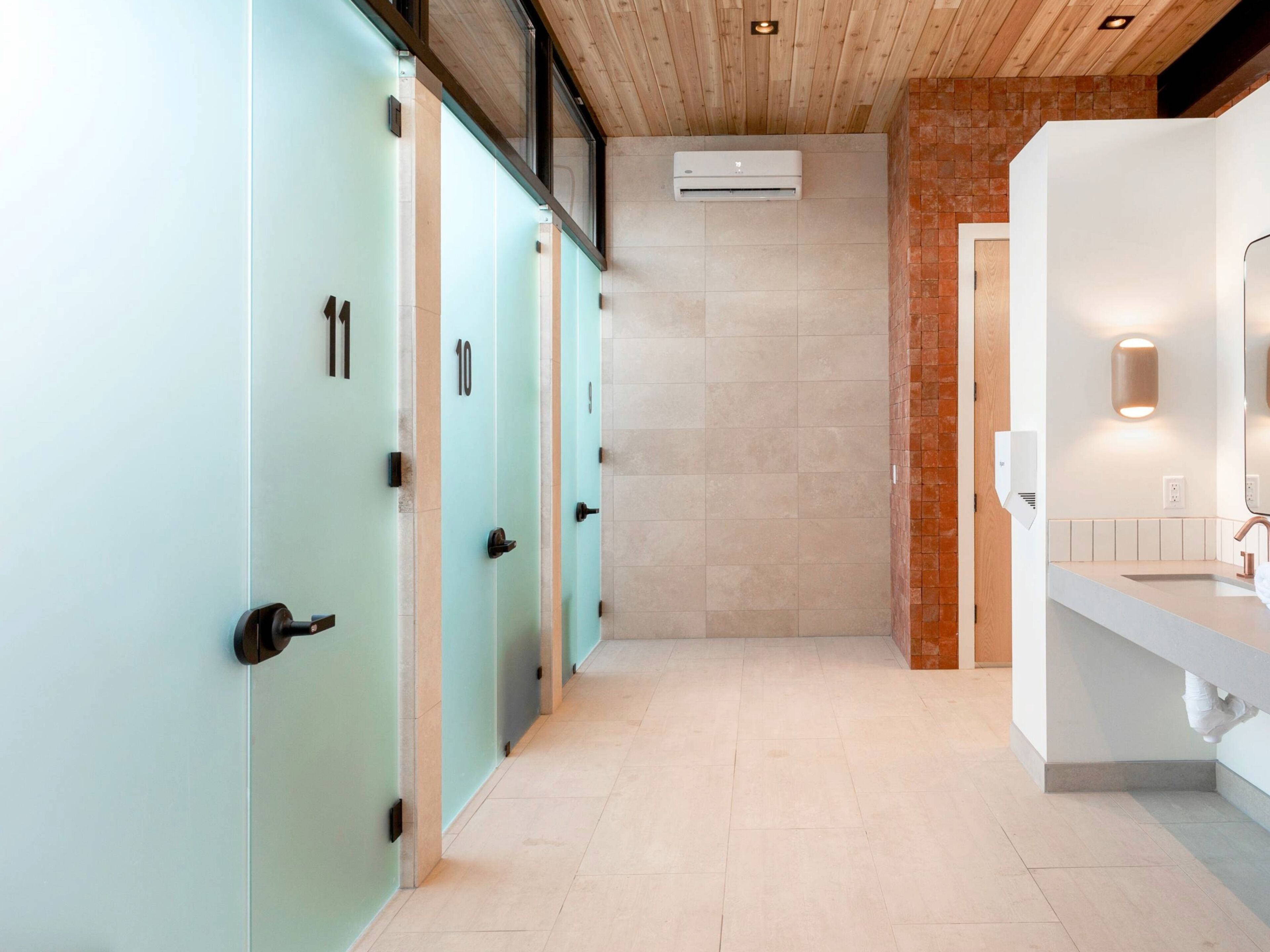 A modern bathroom with light blue lockers, a white sink, and a wooden ceiling.