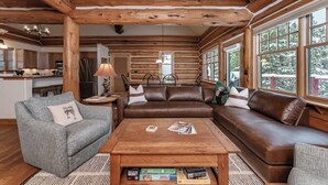 L’intérieur d’une cabane en rondins comprend un salon avec un canapé, une table basse et une cheminée.