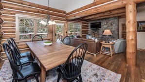 L’intérieur d’une cabane en rondins comprend un coin repas, une cheminée et un mur en pierre.