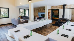 Une pièce spacieuse avec une longue table préparée pour une réunion, une cheminée et un mur en pierre.