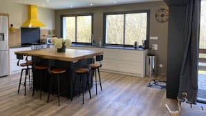 Une cuisine moderne dotée d’un îlot central, de planchers en bois et d’une grande fenêtre qui laisse entrer la lumière naturelle.
