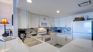 A modern kitchen with white cabinets, a microwave, stove, sink, and a refrigerator. - Stunning ✨ Comfortable and Well Decorated Property 🌺 Incredible Views! 🏖 White Sands 318 (Kailua Kona)