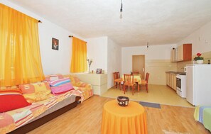 Uma sala de estar acolhedora com sofá, mesa de jantar e cozinha.